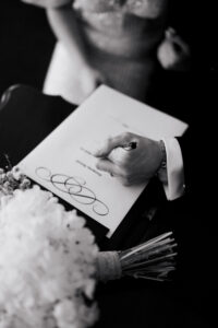 Groom signing the wedding register, black-and-white
