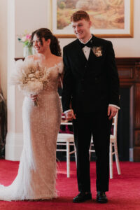Bride and groom smile at wedding guests during ceremony