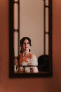 Solo portrait of bride in the reflection of a mirror on the wall