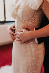 Bride and groom embracing each other, wedding dress details