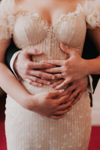 Bride and groom holding each other's hands while reaching for their rings