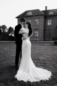 Bride and groom posed together against Tredegar's House in black-and-white