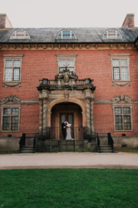 Bride and groom posed together, directed by the photographer at Tredegar House