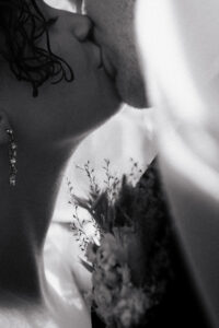 Close-up of the couple sharing a kiss under the veil in black-and-white