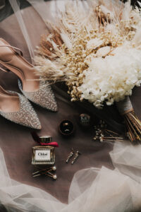 Wedding day details of bride's shoes, bouquet, and rings