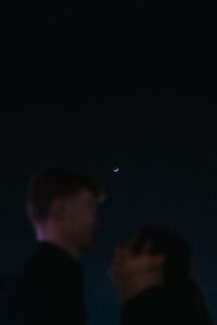 Silhouette portrait of bride and groom with crescent moon in the background