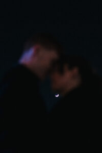 Silhouette portrait of bride and groom resting heads together with the moon behind them