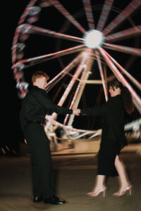 Portrait of couple dancing with a ferris wheel behind them in Cardiff Bay, with motion blur