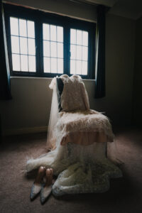 Bride's dress lying on a chair with the veil and shoes nearby