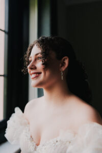 Solo portrait of bride looking out the window smiling