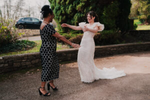 Bride greeting wedding guest with arms out