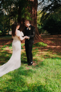 Groom looking at bride and holding her hands in first look