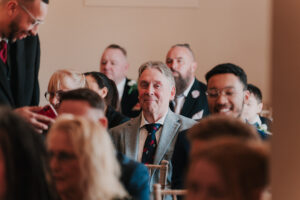 Wedding guest smiling before ceremony begins in registry office, candid moment