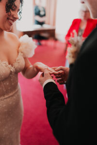 Groom placing wedding band on bride's finger during ceremony