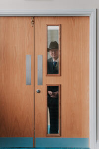 Candid moment of the father of the bride looking through window before the wedding ceremony