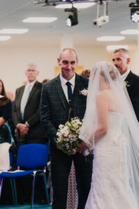 Groom smiling at bride as he sees her