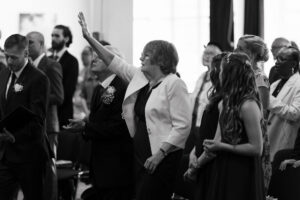 Congregation singing and raising hands in wedding ceremony