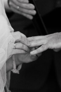 Bride placing wedding band on groom's hand