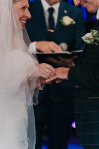 Candid moment of the bride and groom grinning during the ring exchange