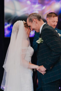 Bride and grooms touching foreheads after sharing first kiss