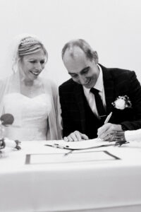 Bride and groom smiling as they sign the wedding register