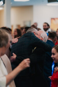 Father of the bride and groom embrace in a spontaneous hug