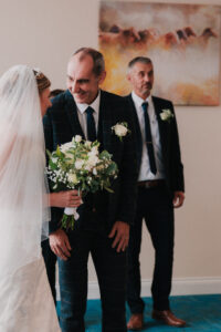 Candid of the groom smiling at the bride