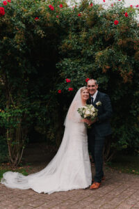 Wedding portrait posed against the park backdrop with red flowers