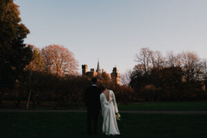 Wide portrait of bride and groom looking at Cardiff Castle