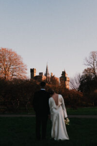 Portrait of bride and groom looking at the sunset on Cardiff Castle