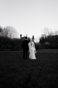 Black-and-white moment of bride and groom looking at Cardiff Castle