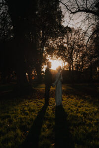 Portrait of bride and groom silhouetted by golden hour sun