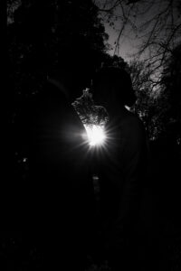 Black and white moment of bride and groom silhouetted by sun