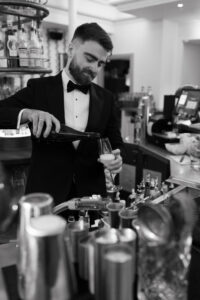 Black-and-white portrait of groom pouring the bride some champagne