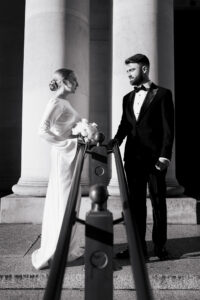 Bride and groom separated by Cardiff Museum pillars in black-and-white