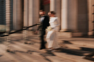Portrait of the bride and groom running down the stairs of the museum with motion blur