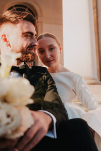 Bride looking into camera while the groom looks away during golden hour