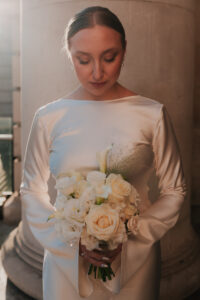 Bride looking down at bouquet during golden hour