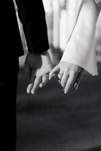 Bride and groom locking pinky fingers together, black-and-white
