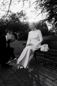 Blurry, black-and-white portrait of groom fixing bride's shoe