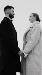 Black-and-white close up of bride and groom holding hands