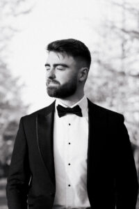 Black-and-white portrait of groom closing eyes