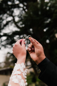 Bride and groom holding wedding rings up to the sky