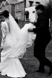 Groom carrying bride's dress at The Celtic Manor Resort, black-and-white