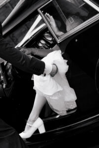 Angled black-and-white portrait of the bride stepping out of the car