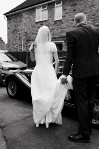 Father of the bride holding the bride's dress