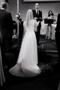 Portrait of the back of the bride's dress in wedding ceremony in Ruislip, London, black-and-white