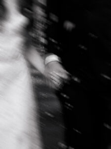 Motion blur portrait of bride and grooms hands together, black-and-white