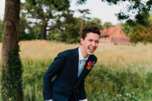 Unposed moment of groom laughing at wedding in The Great Barn
